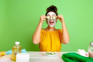 Mujer sonriendo con una mascarilla de pepino y aceite de oliva aplicada en el rostro