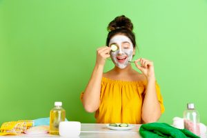 Mujer aplicándose una mascarilla de pepino y aceite de oliva, sonriendo